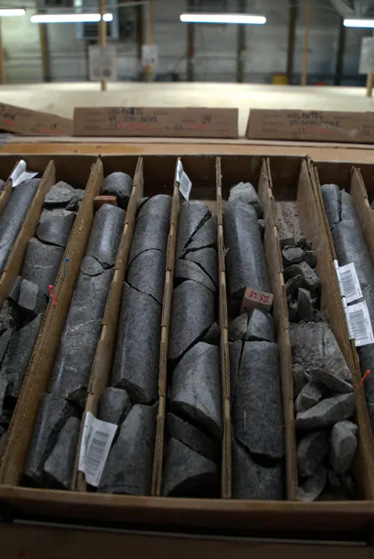 Consulting — core drilling rig on hillside Rock core samples organised in wooden storage boxes in a laboratory